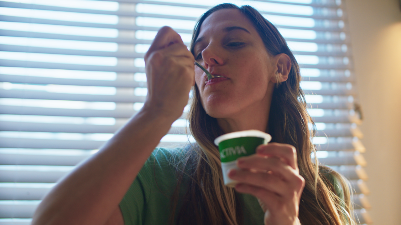 Mujer comiendo Activia para mejorar su microbiota intestinal
